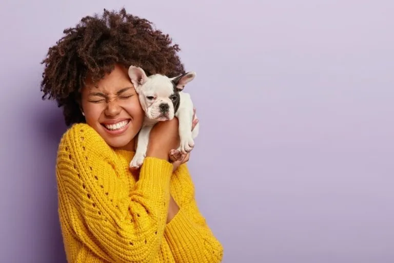 a woman hugging a tiny french bulldog puppy